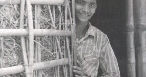 Young boy standing beside a traditional bamboo structure