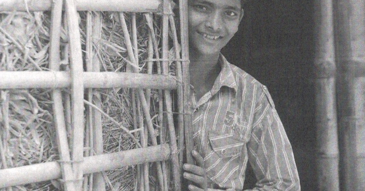 Young boy standing beside a traditional bamboo structure