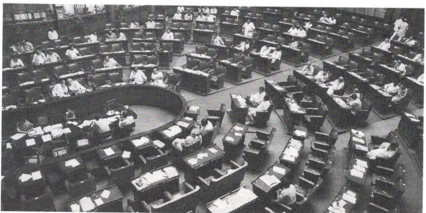 Wide view of a parliamentary chamber with members seated at curved rows of desks